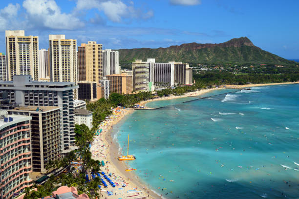 Waikiki Beach, HI, USA July 31. A sweeping aerial view of the sands on the shore of Waikiki Beach. Hawaii extends past the hotels and resorts to Diamond Head Mountain
