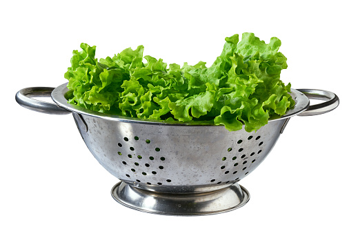 Colander with green lettuce salad leaves isolated on white background.