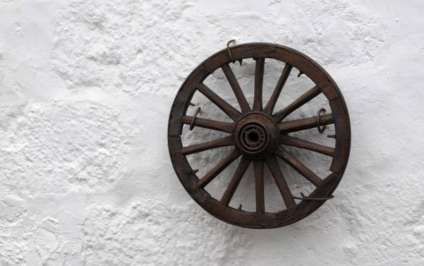 istock Old wooden wheel on a white stone wall background.Retro style concept for interior design. 2146836025