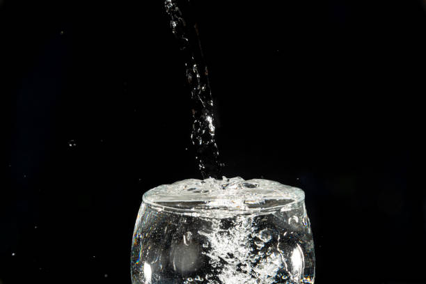 istock Close-up of a transparent glass cup with water inside and drops making a splash. 2146837971