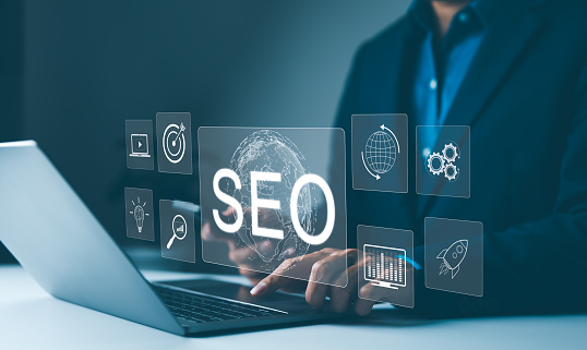SEO strategy tools and optimization concepts. Marketer working on SEO strategy with laptop and virtual screen showing global SEO optimization icons. attract organic traffic, digital marketing, search,