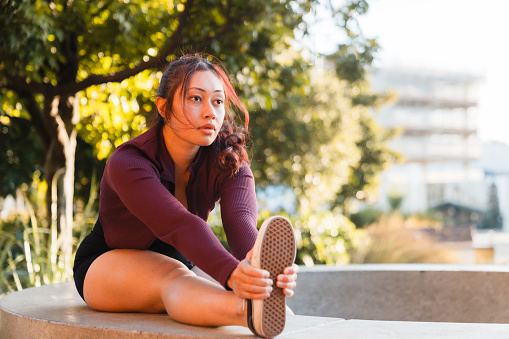Young Pacific islander woman doing yoga , stretching outdoors, healthy lifestyles concept.