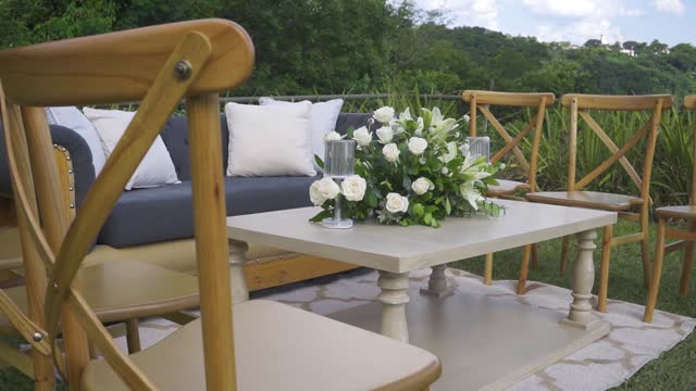A wooden table with a vase of white flowers and a couple of chairs and furniture around it.