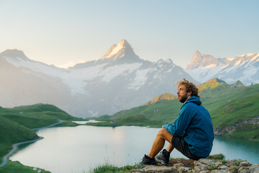Serene man looking at Bachalpsee in Swiss Alps in the morning in summer