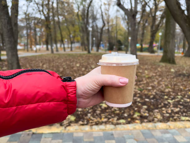 istock Hand holding coffee cup on autumn park background 2146926115