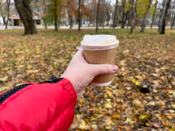 istock Hand holding coffee cup on autumn park background 2146934376