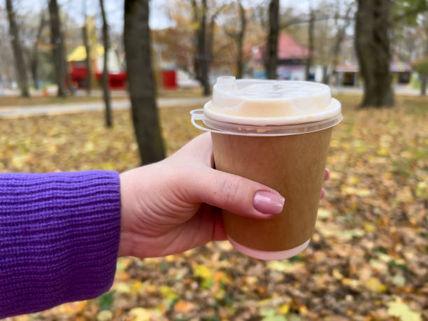 istock Hand holding coffee cup in autumn park with leaves on background 2146935405