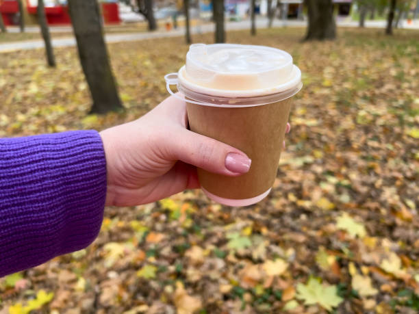 istock Hand holding coffee cup in autumn park with leaves on background 2146941107