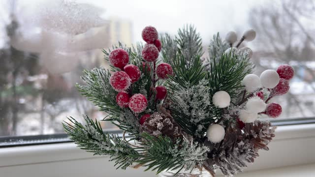 Christmas decoration. Artificial pine branch with red berries in the frost. Festive decorations. The work of a designer-decorator. On the eve of Christmas.