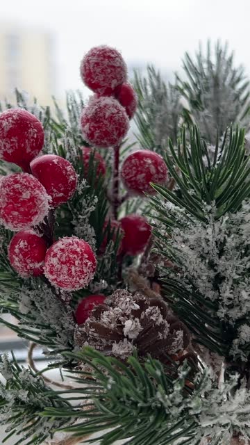 Christmas decoration. Artificial pine branch with red berries in the frost. Festive decorations. The work of a designer-decorator. On the eve of Christmas.