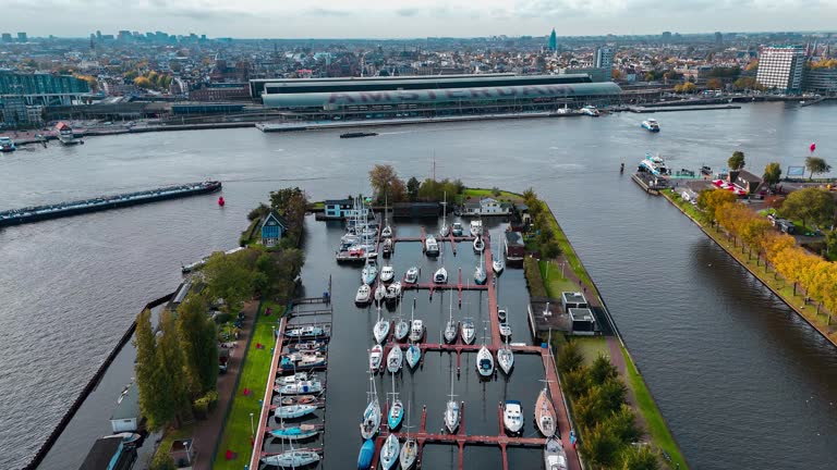 Aerial drone view Amsterdam Central Train Station with Amsterdam sign on roof. Bird's eye view autumn cityscape.