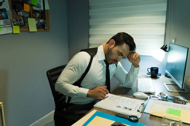 istock Investigator focused on analyzing documents at cluttered desk, surrounded by case evidence 2146982733