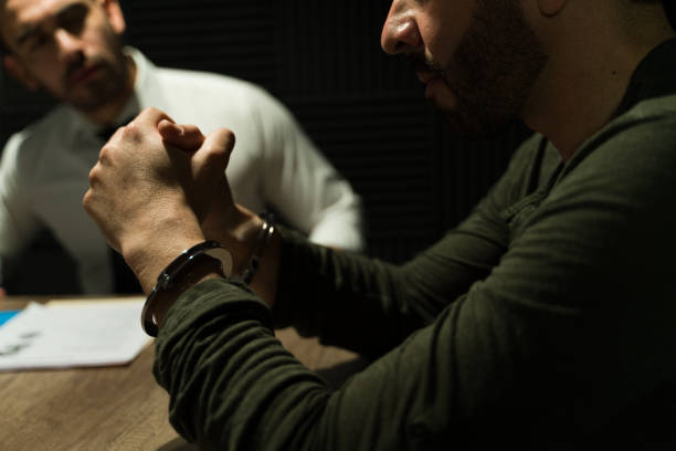 istock Detective interrogating a handcuffed suspect in the shadows under a spotlight 2146988811