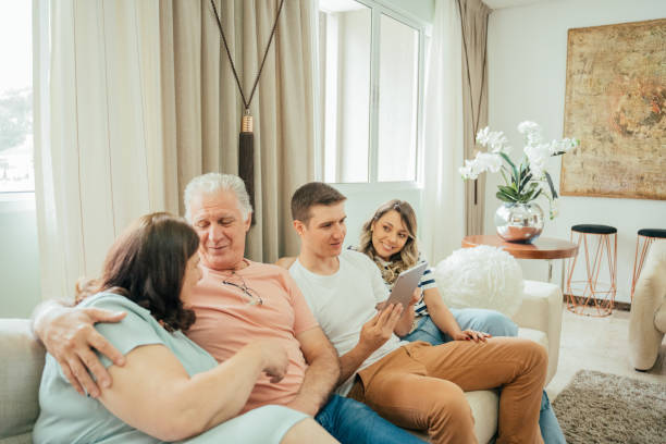 istock Multigenerational family looking at tablet sitting on sofa 2147025593
