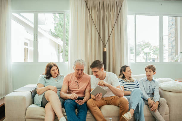 istock Multigenerational family looking at tablet sitting on sofa 2147026614