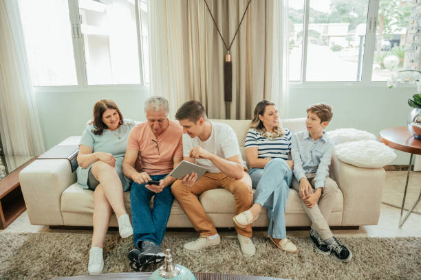 istock Multigenerational family looking at tablet sitting on sofa 2147026616