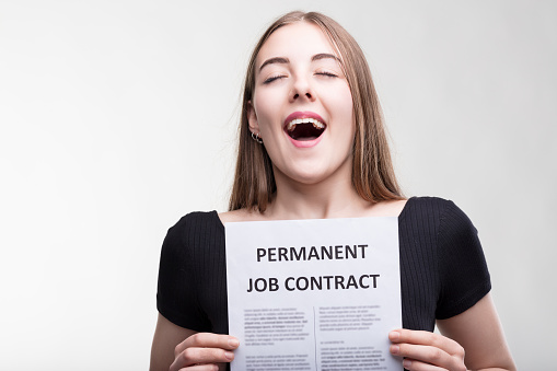 Exuberant young woman celebrates holding a permanent job contract