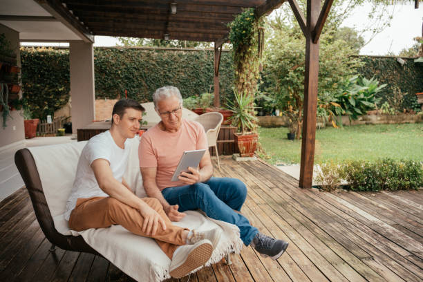 istock Father and son looking at tablet sitting on porch 2147032255