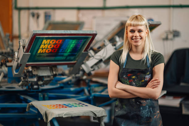 istock Confident print shop worker near screen printing press smiling at camera 2147087616