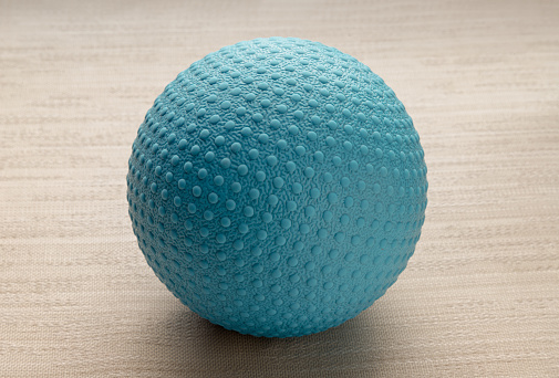 Lacrosse massage ball on sofa cushions. Blue rubber lacrosse ball, Spherical ball, Space for text, Selective focus.