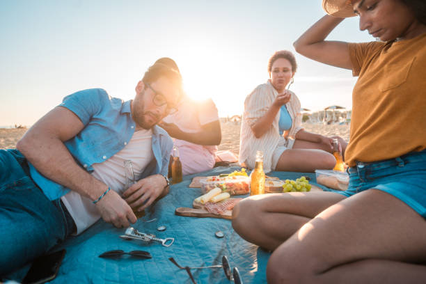 istock Young Multi-Ethnic Group Enjoying Snacks and Beer at the Beach 2147100611