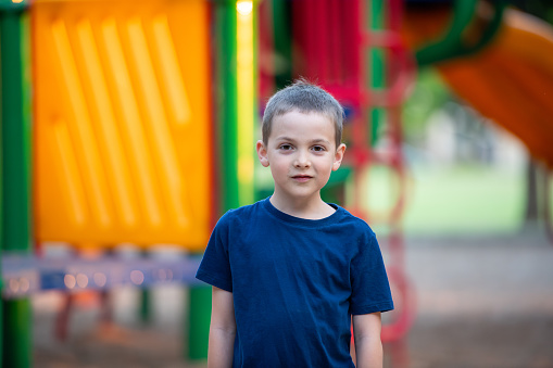 Smiling caucasian with short hair little boy looking at the camera in a park