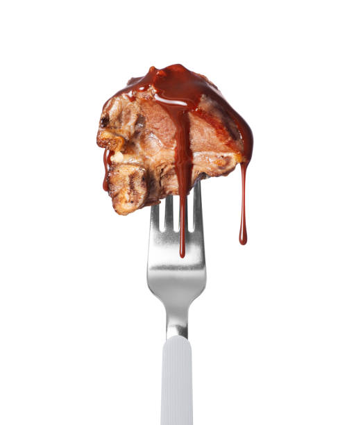 istock Fried beef steak poured with sauce on a fork close up on a white background 2147196399