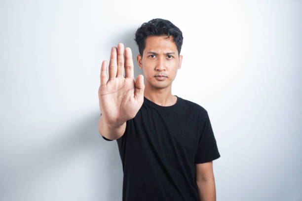 istock Asian handsome man over isolated background making stop gesture 2147250577