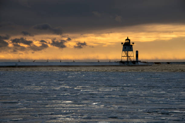 Grand Marais Harbor Lighthouse on a cold February morning with ice in the bay and a subtle orange sunrise