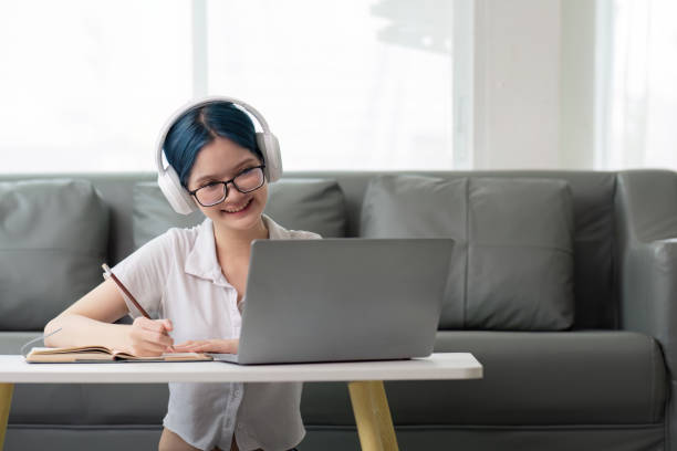 istock Happy young woman teenage wearing headphones writing note. student online learning class study online video call zoom teacher with laptop and book 2147405868