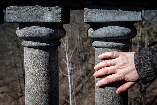 Hand on stone pillar,  exploring the constructs of  architectural element.