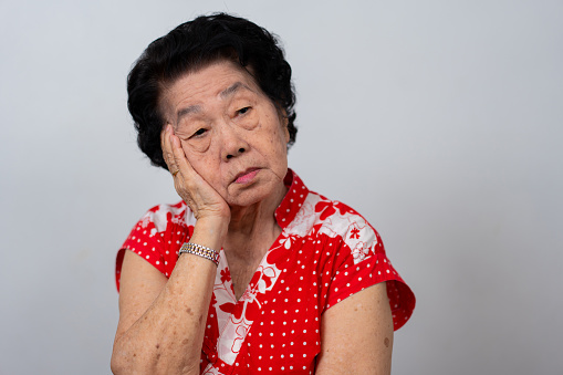 Depressed Asian senior woman lonely disappointed and lose memory in isolated white background. Portrait old woman ill sick depression disease feel sad and unhappy, dementia, health problems concept.