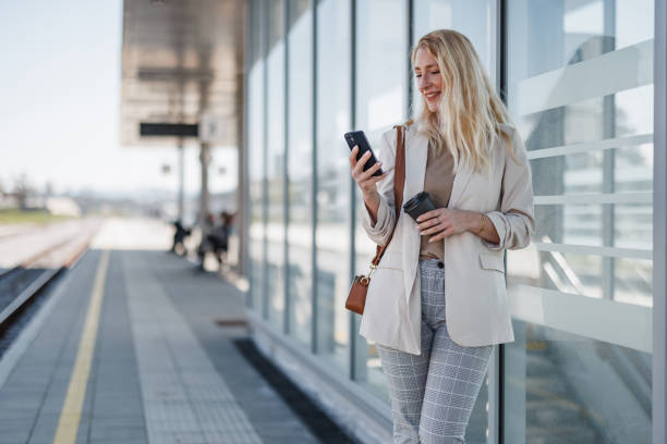 istock Smiling Businesswoman With Smart Phone at Train Station 2147487568