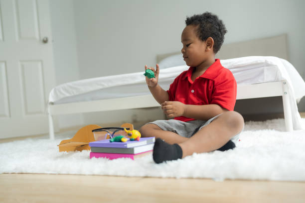 Cute little boy making things from plasticine on the ground Follow your imagination with a smiling, bright and determined face.