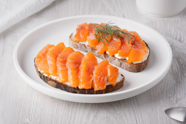 istock Rye sandwich with salmon and cream cheese on white wooden table 2147490088