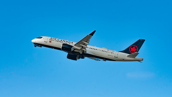 An Air Canada Airbus A220 retracting it's landing gear as it ascends from Seattle-Tacoma International Airport (Sea-Tac), USA, on it's way north to Vancouver International Airport, Canada.