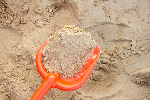 Sand collected in an orange spade.