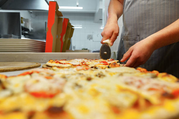 istock Chef Cutting Freshly Baked Pizza in a Commercial Kitchen Setting 2147499543