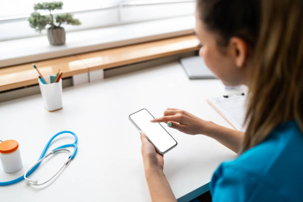 istock Female doctor in blue medical scrubs using mobile phone while working at the ordination 2147500231