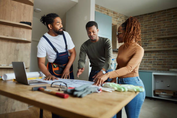 istock Happy black couple and manual worker working on blueprints at home. 2147501469