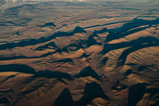 Captured from above, this striking aerial shot showcases the mesmerizing landscape of the Bolivian desert mountains. Nature's artistry is on full display as geometric patterns, including intricate hexagonal formations, adorn the rugged terrain. The scene is a captivating blend of rugged peaks, barren expanses, and endless skies, offering a glimpse into the breathtaking beauty of our planet's natural wonders.
