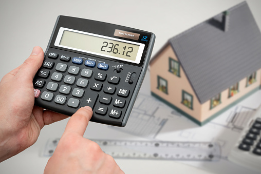 House construction concept. Man calculates the cost of building a house on a calculator