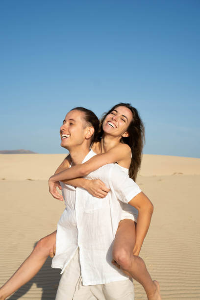 istock Happy man walking and carrying girlfriend piggyback 2147505151