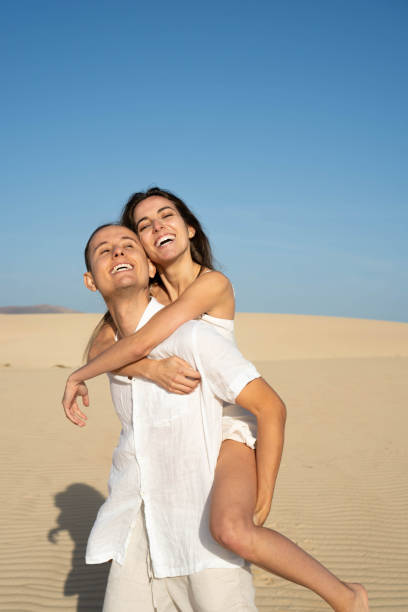 istock Happy couple enjoying piggyback on sandy terrain 2147507221