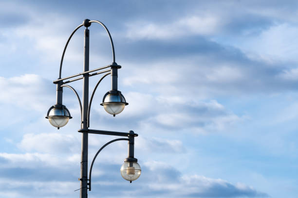 The dramatic cloudy sky serves as a backdrop, with silhouetted street lights evoking an urban atmosphere