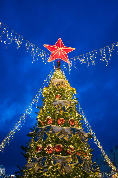 istock Christmas tree with red star on top on evening street. 2147507397