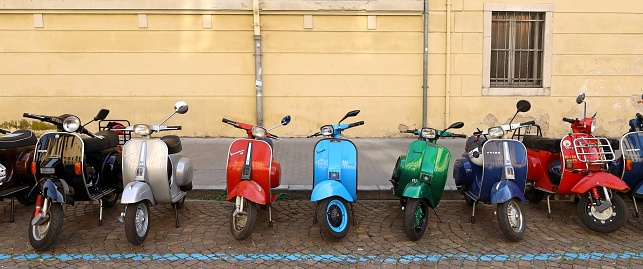 Udine, Italy. April 7, 2024. Vintage multicolor Vespa mopeds in a row before an old timer scooter parade. Front view, no people.