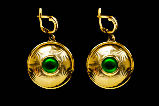 Vintage large golden earrings with emeralds isolated on black background