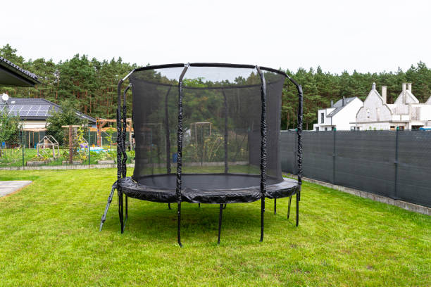 istock Large childrens jumping trampoline with protective net and closed zipper, standing in the garden, visible mesh masking the fence. 2147511530
