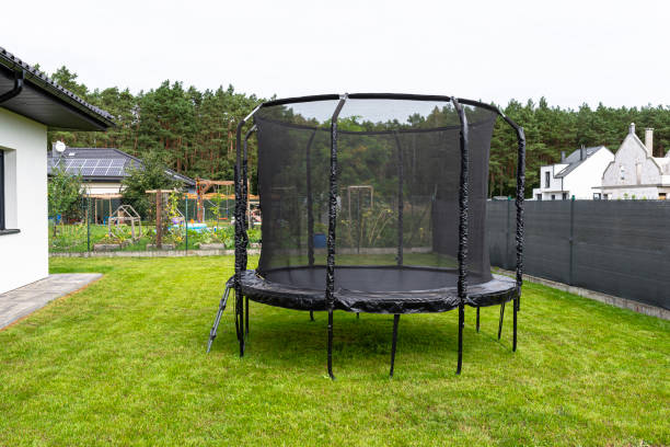istock Large childrens jumping trampoline with protective net and closed zipper, standing in the garden, visible mesh masking the fence. 2147511586